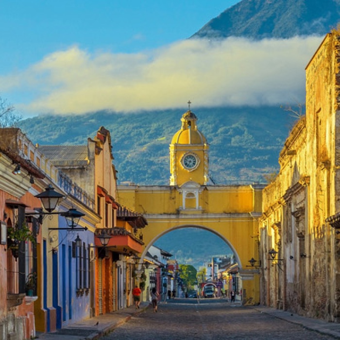 The historic city of Antigua at sunrise with a view over the main street and the Catalina arch and the Agua volcano in the background, Guatemala.
