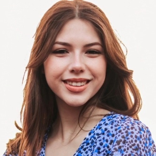 Student in a blue top smiles at camera