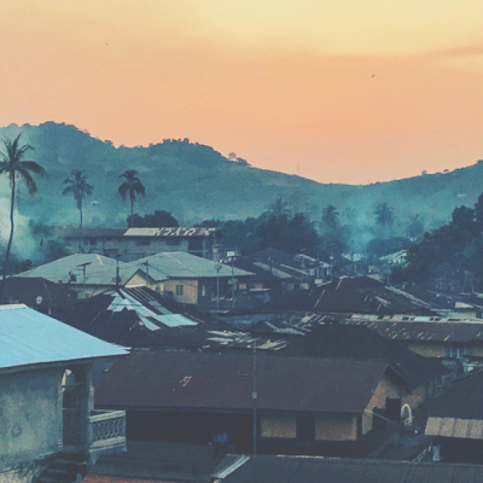 Rural town in Sierra Leone with tropical trees and orange sky