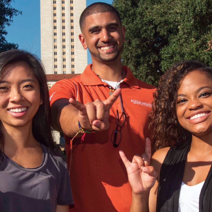 students doing a hook em in front of the tower