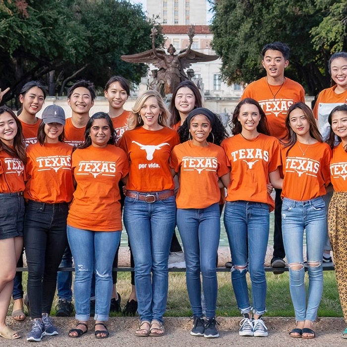 Group of mixed race students standing in front of the UT Littlefield Fountain wearing burnt orange UT shirts
