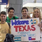 UT administrators and students hold a sign that reads "Welcome to Texas Fulbright Argentina Scholars" at the Austin airport.