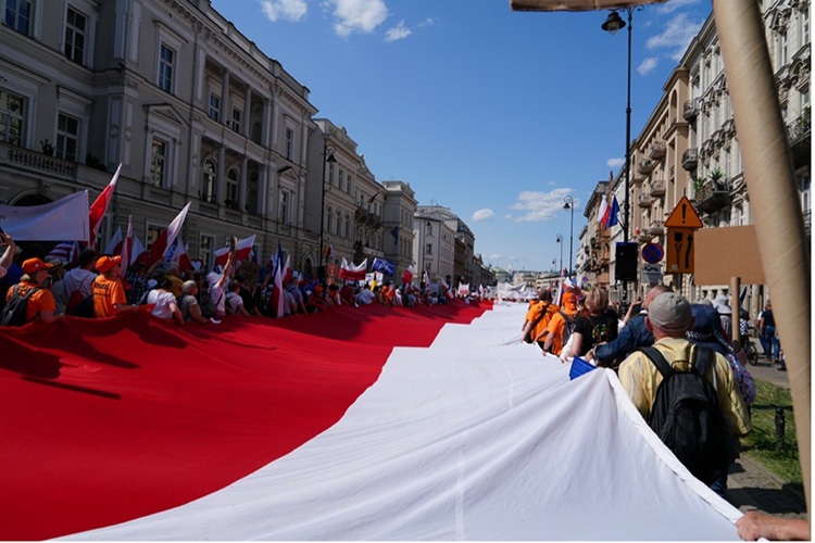 Protesters carry the Polish flag through Warsaw in 2023